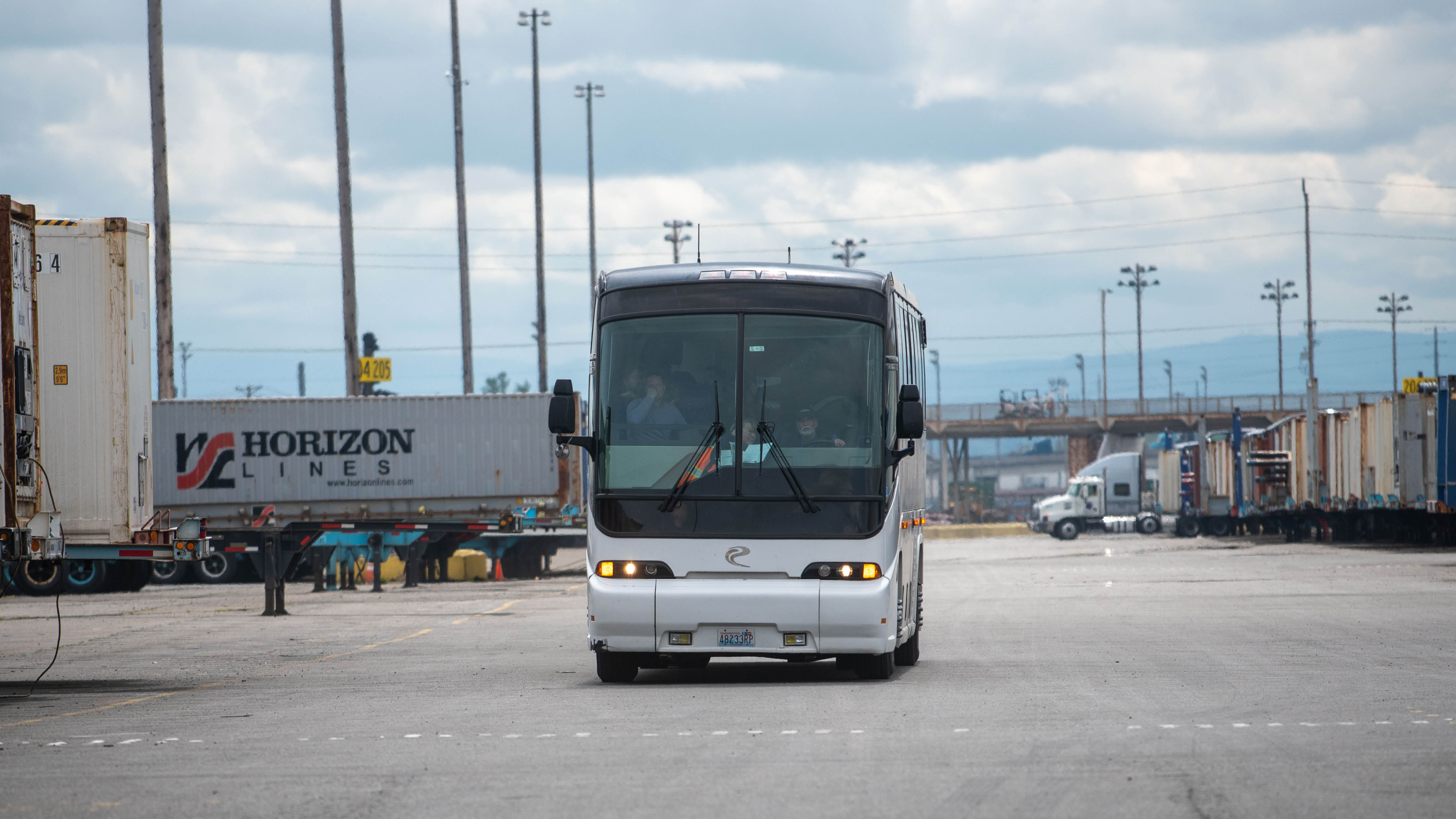 The front of a white and black bus in a parking lot. 