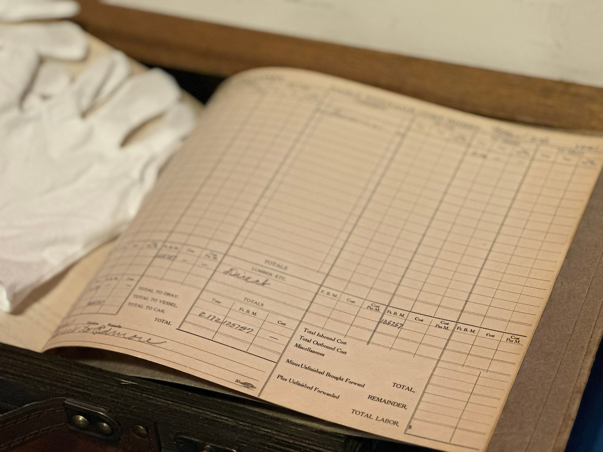 A closeup shot of an old ledger book with white gloves next to it. 