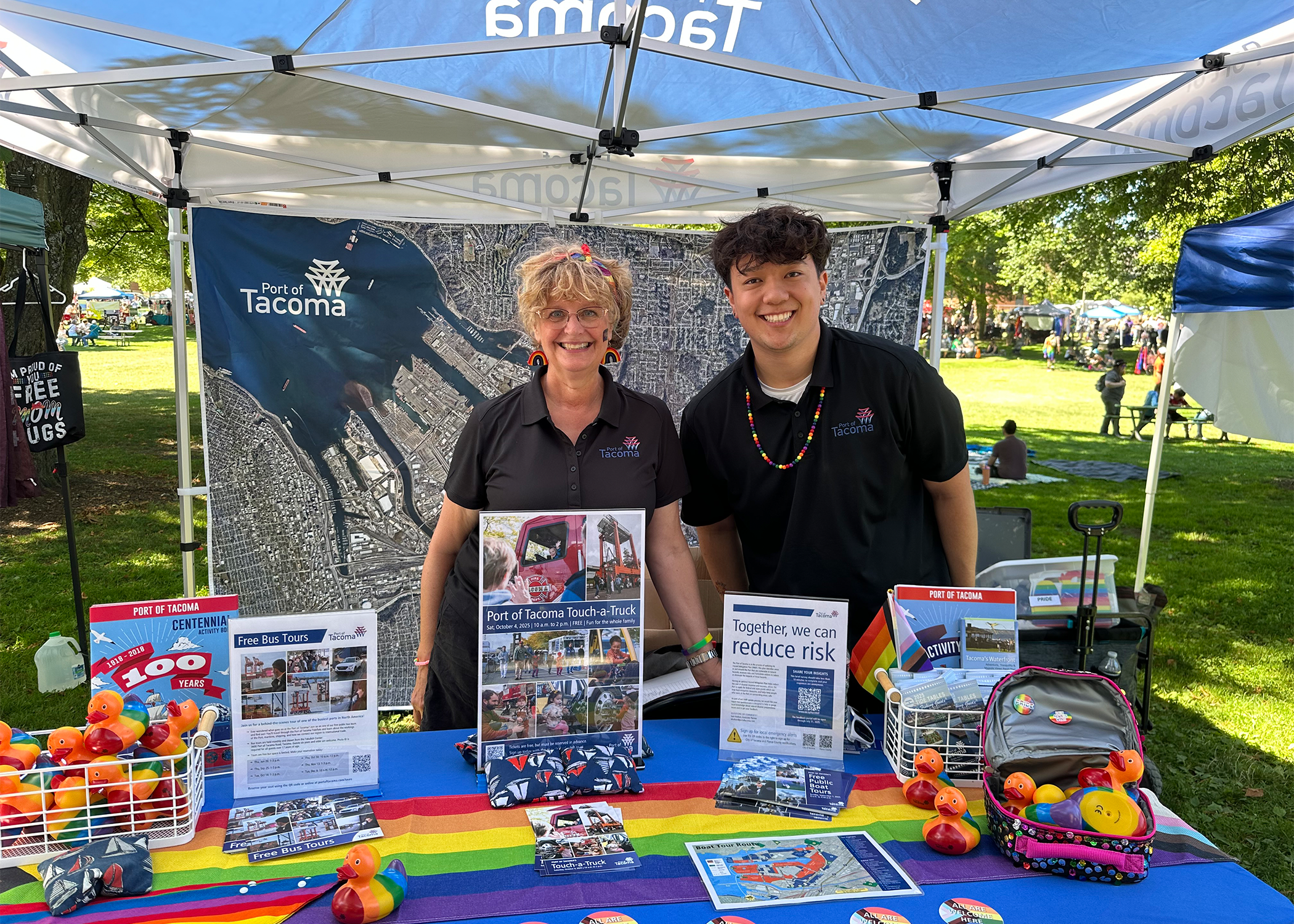 A man and woman stand smiling at a pride booth.