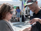 A man points at a piece of paper while speaking to a woman.