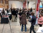 A group of people walk through an event filled with display booths. 