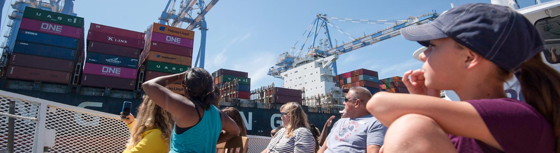 photo of people on a boat looking up at a crane