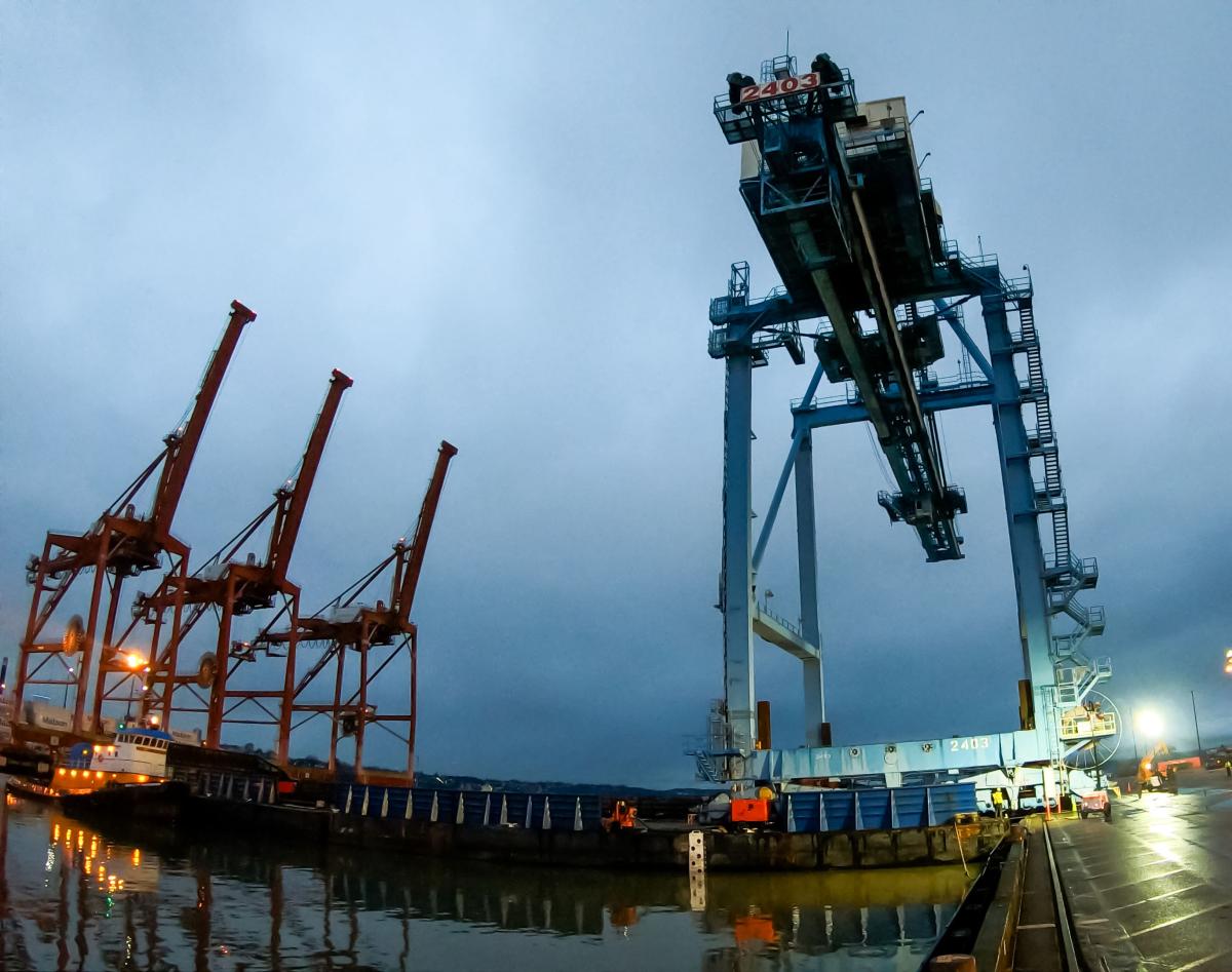 Four large cranes on a terminal on a cloudy afternoon.