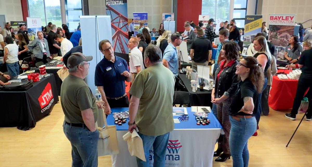 A group of people at a networking event in front of a booth.