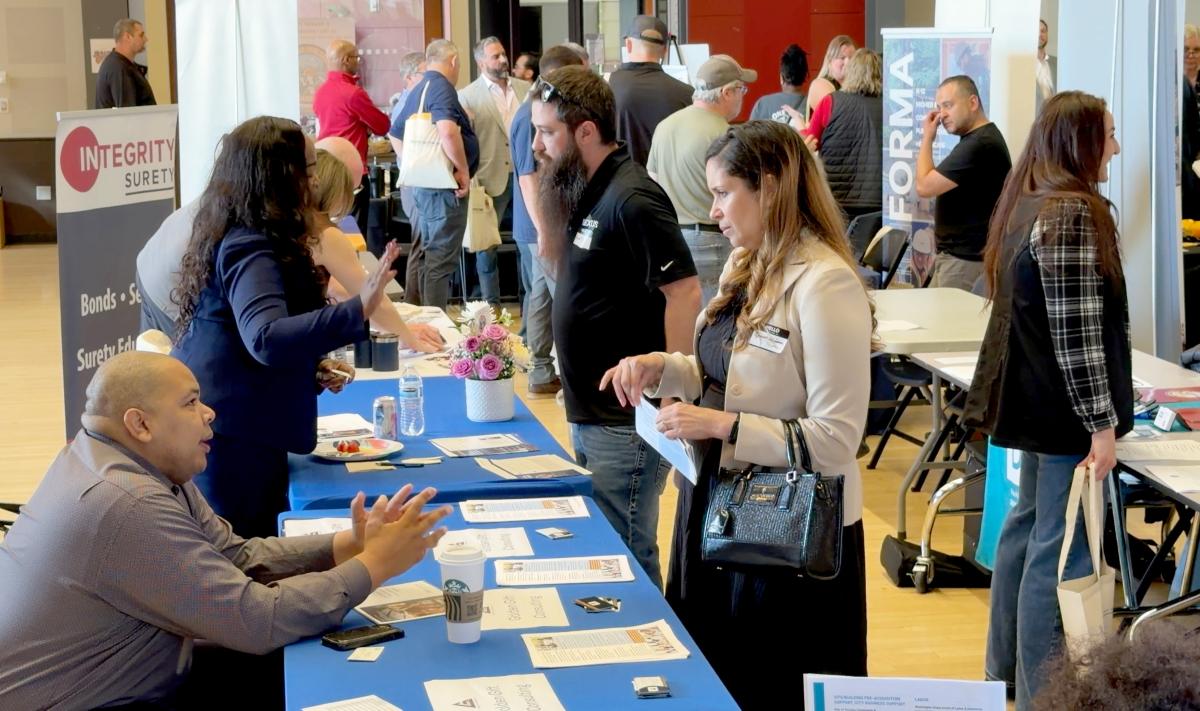 People approach tables and connect at a networking event.