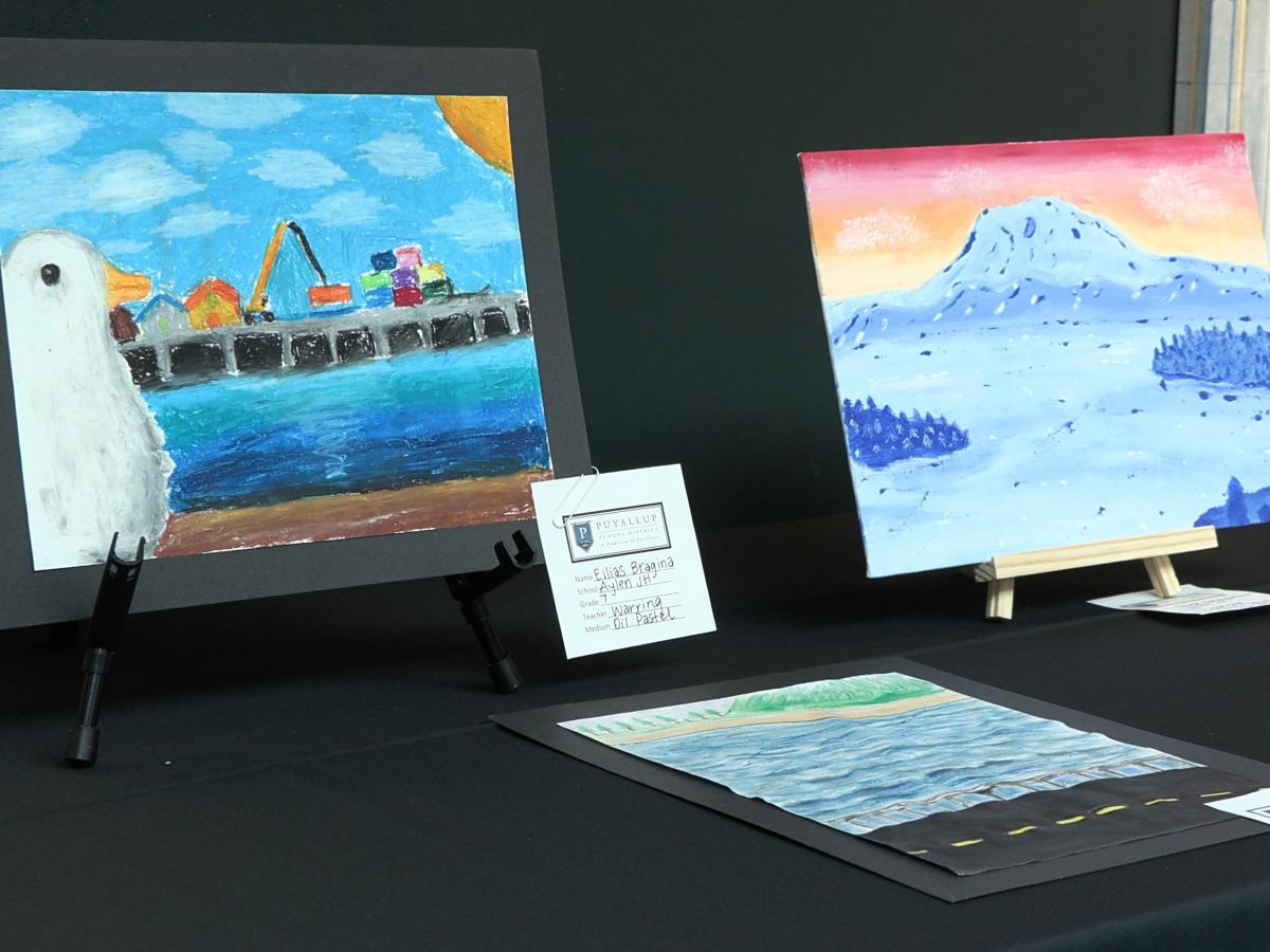 Three pieces of student art are displayed on a table in the Port Admin Building.