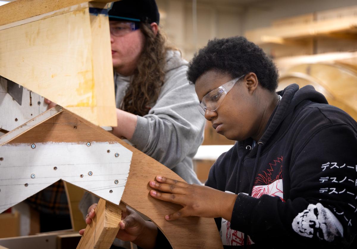 Students at the Industrial Design Engineering and Art (IDEA) high school works on construction of wooden boat the class designed and is working to assemble.