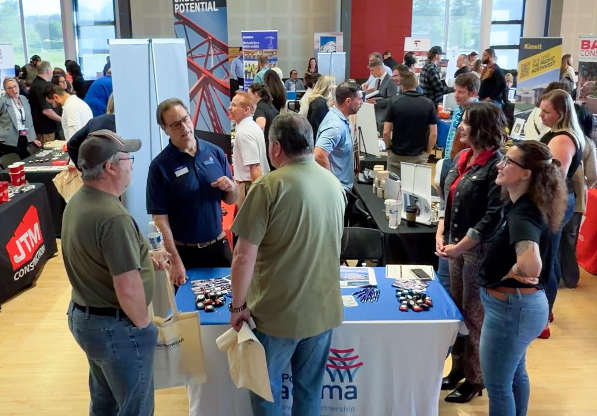 A group of people at a networking event in front of a booth.