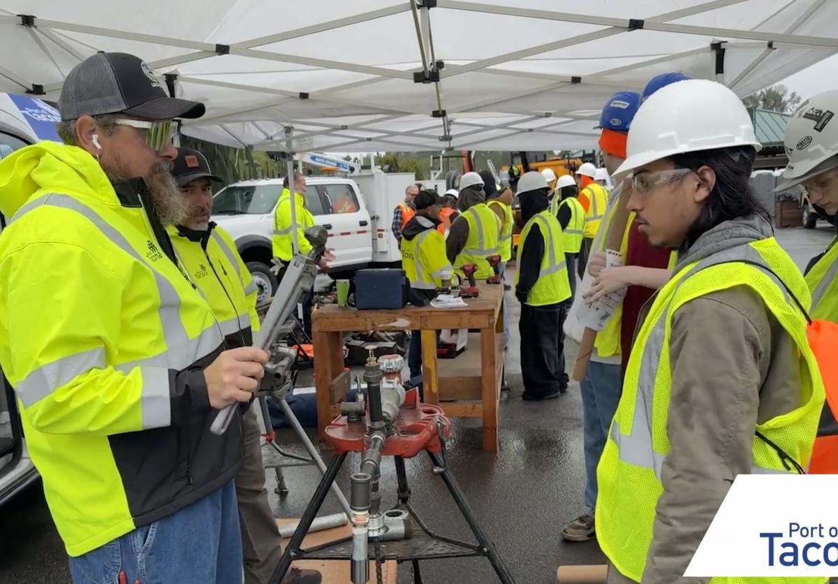 A student in a reflective vest and hard hat speaks to a vendor at Pierce County Construction Career Day 2026